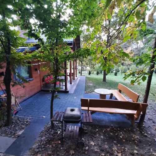 a park with two benches and a table and trees at Roztocze 3 kroki od sosny in Zamość