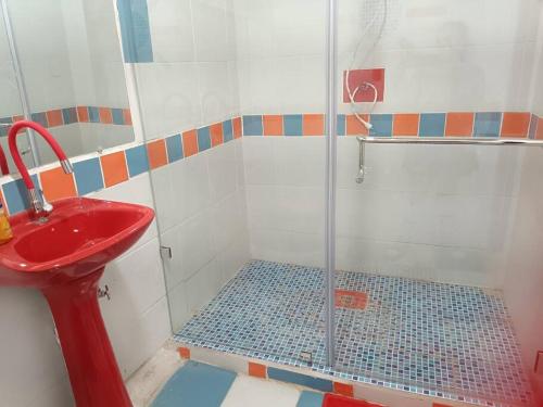ein Bad mit einer Dusche und einem roten Waschbecken in der Unterkunft Nebraska's Corner cerca de aeropuerto de Tababela in Yaruguí