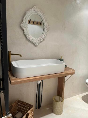 - un lavabo blanc sur une table en bois avec un miroir dans l'établissement Les chambres de Mila, à Allériot