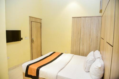 a bedroom with a bed and a television in it at Hotel De Alommah Kubwa Abuja in Abuja