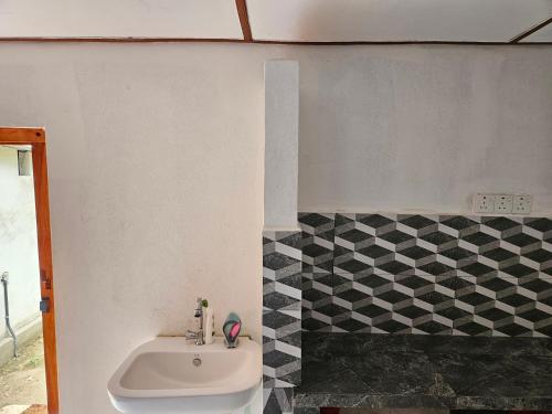 a bathroom with a sink and a black and white tiles at Saraswathy Inn in Mulai