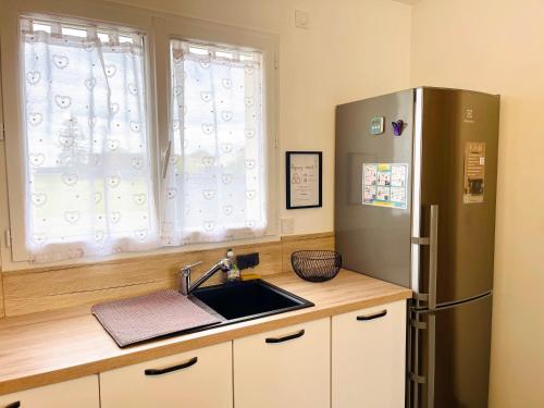 a kitchen with a stainless steel refrigerator and a sink at Petite maison au calme in Poupry