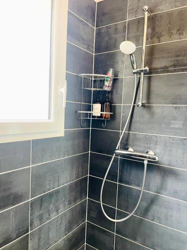 a shower with a hose on a tiled wall at Petite maison au calme in Poupry