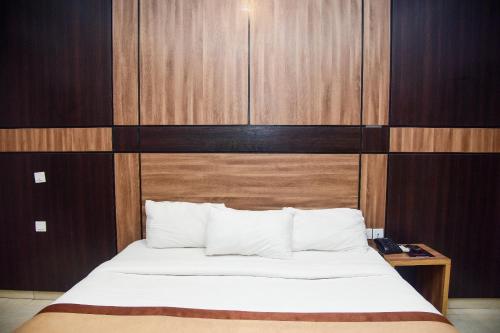 a bedroom with a bed and a wooden wall at Hotel De Alommah Kubwa Abuja in Abuja