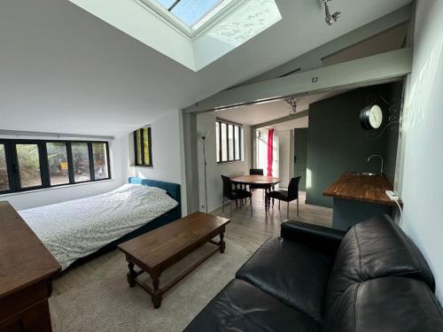 ein Schlafzimmer mit einem Bett, einer Couch und einem Tisch in der Unterkunft Petite maison indépendante avec parking in Vétheuil
