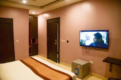 a bedroom with a bed and a flat screen tv on the wall at Hotel De Alommah Kubwa Abuja in Abuja