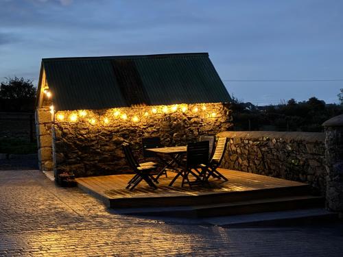 a table and chairs on a patio with lights at Mournes Family Cottage with Hot Tub in Hilltown