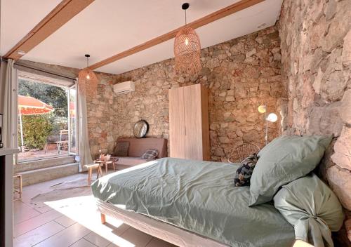 Un dormitorio con una cama y una pared de piedra. en Le Mazet en Provence 25m2, en Le Tignet