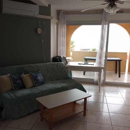 un salon avec un canapé vert et une table dans l'établissement Vue Mer Panoramique WIFI gratuit, au Barcarès