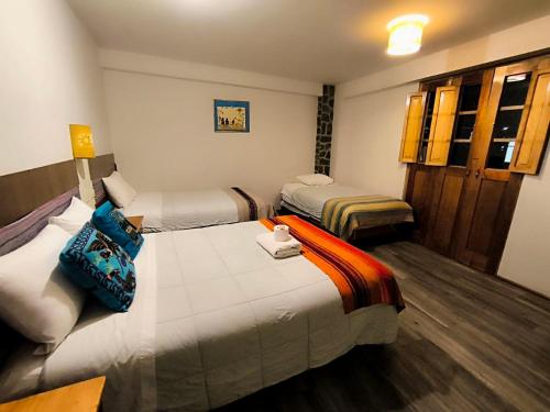 a hotel room with three beds in a room at hostal Balcon de Piedra in Urubamba