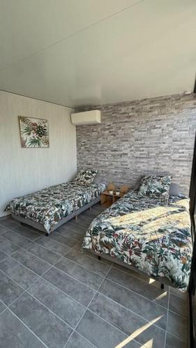 une chambre avec deux lits et un mur de briques dans l'établissement Aloha Studio &SPA en bordure de garrigue, à Fleury