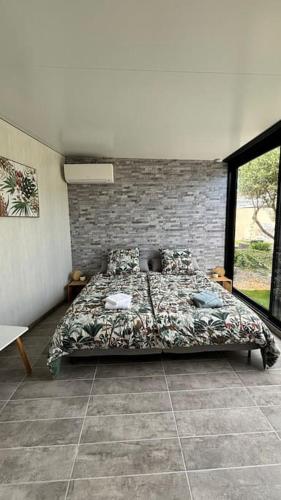 un lit dans une chambre avec un mur de briques dans l'établissement Aloha Studio &SPA en bordure de garrigue, à Fleury