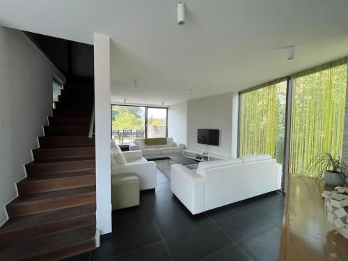 a living room with white furniture and a staircase at Vakantiehuis Tube nabij Brugge in Bruges