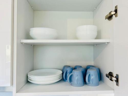 einen Schrank mit Tellern und Schalen darin in der Unterkunft Modern Danube Apartment with Balcony & Free Parking in Wien