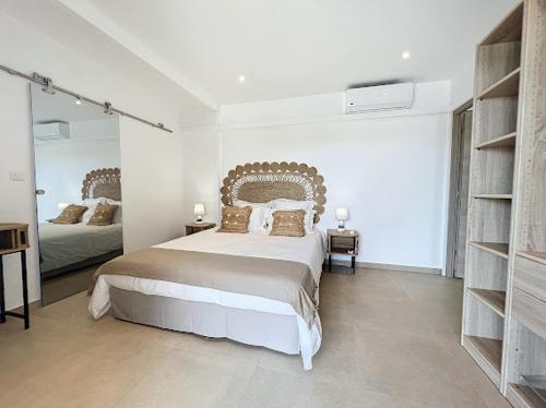 a white bedroom with a large bed and a mirror at Nakolodge - 2 chambres -piscine et jardin privatifs in Sainte-Anne