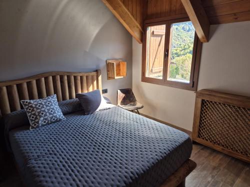 Un dormitorio con una cama con edredón azul y una ventana. en Alojamientos Ruraltena, en Piedrafita de Jaca
