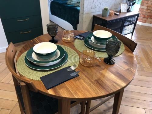 a wooden table with black and white dishes on it at Witkacy Apartament in Słupsk