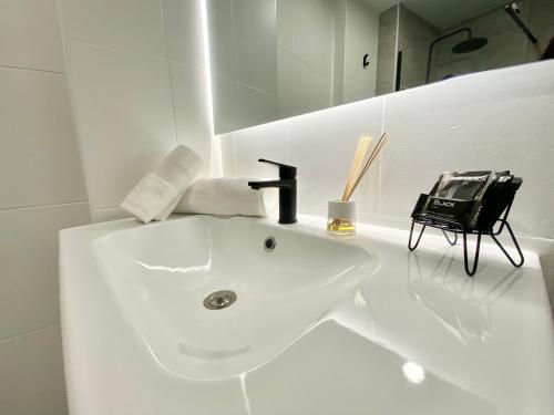 ein weißes Badezimmer mit einem Waschbecken und einem schwarzen Wasserhahn in der Unterkunft Balcón de la Paz in Antequera