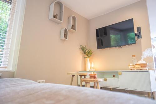 a bedroom with a flat screen tv on the wall at Wellnesshuisje Bunga Baco in Lanaken