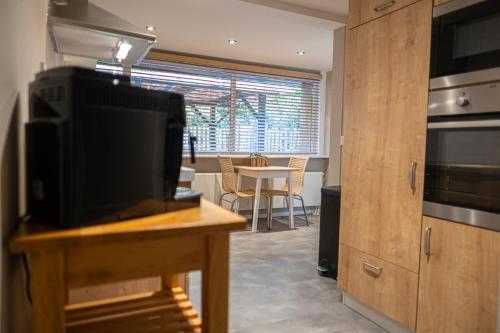 a kitchen with a television and a table with a dining room at Wellnesshuisje Bunga Baco in Lanaken