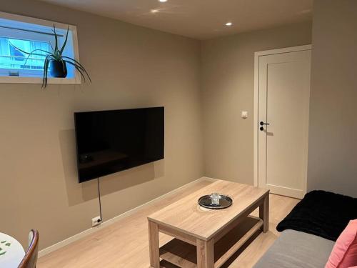 ein Wohnzimmer mit einem Tisch und einem Flachbildfernseher in der Unterkunft Cosy apartment close to Tromsø airport in Kvaloysletta