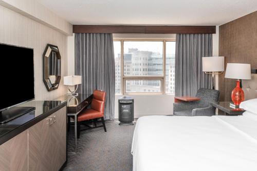 a hotel room with a bed and a desk and a television at Sheraton Indianapolis City Centre Hotel in Indianapolis