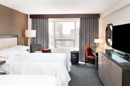 a hotel room with two beds and a flat screen tv at Sheraton Indianapolis City Centre Hotel in Indianapolis