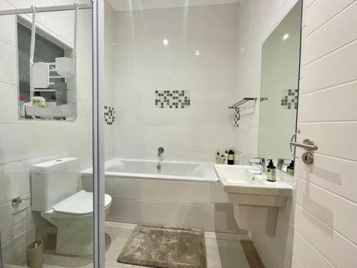 a bathroom with a tub and a toilet and a sink at Sunningdale White House Accomodations in Cape Town