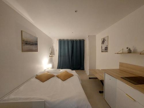Un dormitorio con una gran cama blanca con dos almohadas. en Studio confort proche de la mer sur la côte d'Emeraude - Le Minihic sur Rance, en Le Minihic-sur-Rance
