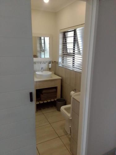 a bathroom with a sink and a toilet and a mirror at Banana Beach Club-RY in Port Shepstone