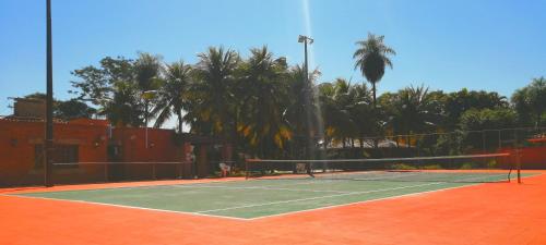 a tennis court with palm trees in the background at BauHouse Comfort Suites Asuncion in Asuncion