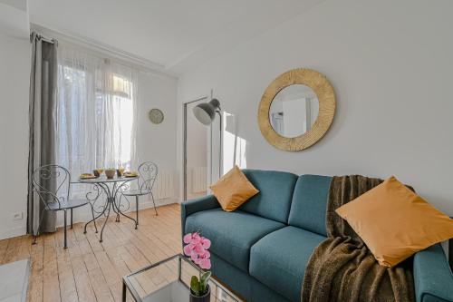 un salon avec un canapé bleu et une table dans l'établissement Le Poétique niché au pied du Sacré-Cœur, à Paris