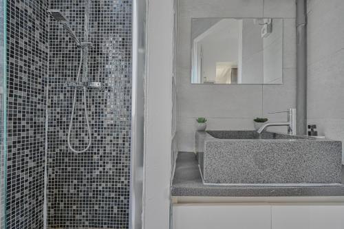 une salle de bain avec un lavabo et une douche avec un miroir dans l'établissement Le Poétique niché au pied du Sacré-Cœur, à Paris