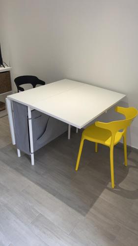 a white table and a yellow chair in a room at Beau studio in Élancourt