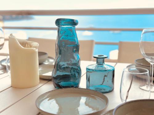 une table avec des bouteilles et des verres en verre bleu dans l'établissement 5mn Monaco - Terrasse vue mer - Parking - EA, à Beausoleil