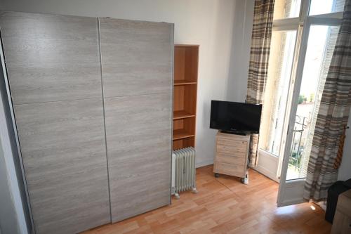 Cette chambre comprend un grand placard gris et une télévision. dans l'établissement Chambre meublée Cannes, à Cannes