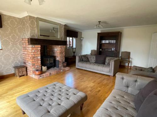 a living room with a couch and a fireplace at Spacious Home, 6 large bedrooms, full sky package, sleeps 14 in Pattishall