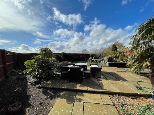 a patio with chairs and a table in a yard at Spacious Home, 6 large bedrooms, full sky package, sleeps 14 in Pattishall