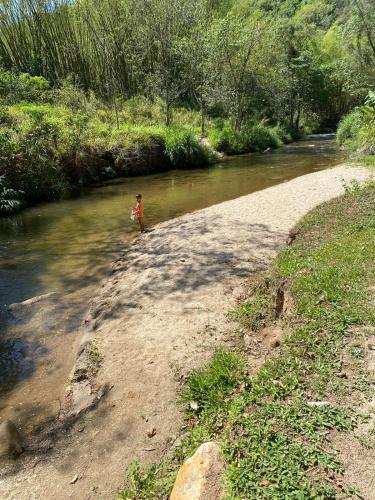 a child standing on the side of a river at Chalés Praias do Sana in Macaé