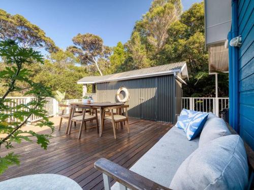 a patio with a table and a couch on a deck at The Tree Tops Oasis in Paihia