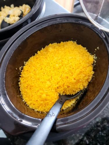 a pot filled with yellow rice with a spoon in it at BOB Suítes in Porto De Galinhas