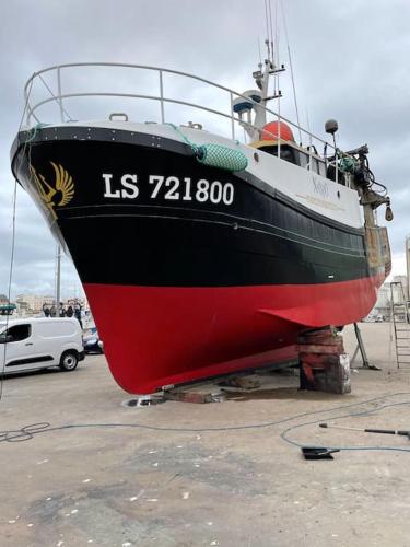 un bateau noir et rouge assis à terre dans l'établissement Louez Notre Bateau Immobilisé !, à Grosbreuil