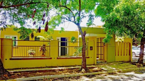 una casa amarilla con árboles delante de ella en Villa Serena, en San Juan