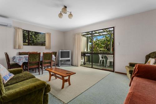 a living room with two couches and a table at The Treehouse- Whanarua Bay in Te Kaha