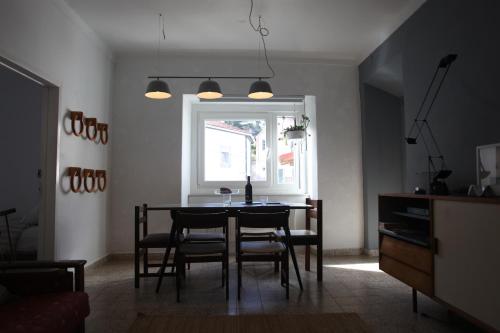 a dining room with a table and chairs and a window at ribeira dos marinheiros vermelho in Sintra