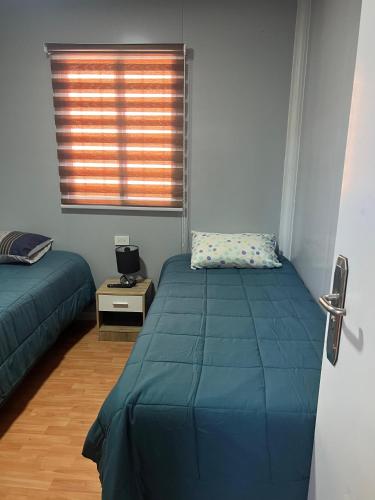 a bedroom with two beds and a window at Hospedaje Oasis Modulares in Calama