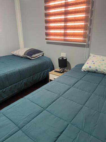 a bedroom with two beds and a window at Hospedaje Oasis Modulares in Calama