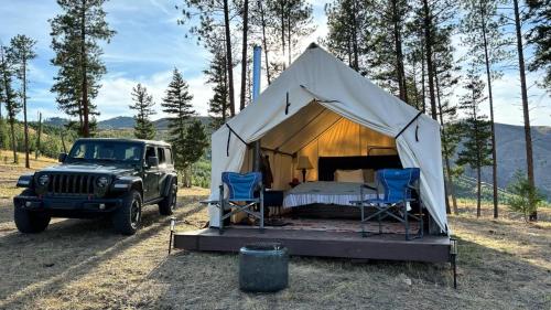 a tent with a bed and two chairs and a jeep at Tent 2 Oxen-Le-Fields Montana in Conner
