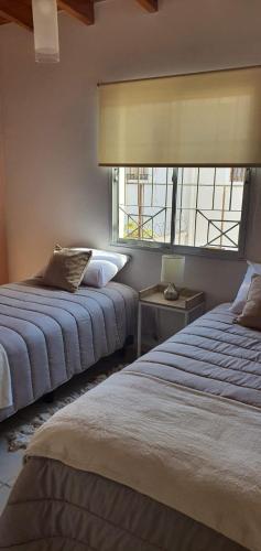 a bedroom with two beds and a window at Aguaribay Deptos Mendoza in Guaymallen
