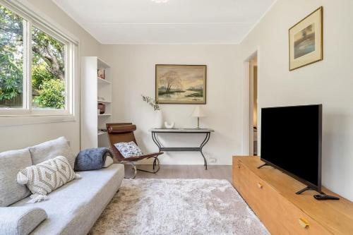 a living room with a couch and a flat screen tv at Charming Blue Mountains Cottage Katoomba in Katoomba